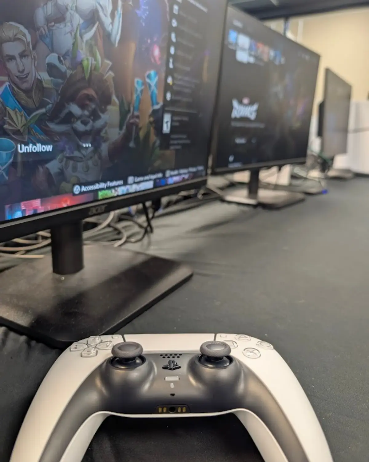 A video game controller on a table in front of computer monitors.